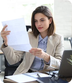 Zbliżenie na bizneswoman trzymającą stos dokumentów biurowych i teczek, organizującą papiery w profesjonalnym środowisku pracy.