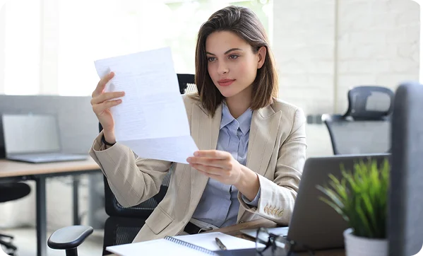 Zbliżenie na bizneswoman trzymającą stos dokumentów biurowych i teczek, organizującą papiery w profesjonalnym środowisku pracy.